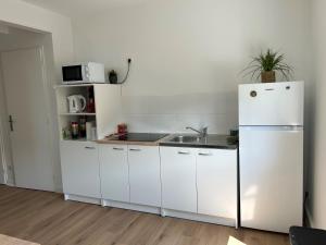 a white kitchen with a refrigerator and a sink at Appartement proche A43, proche gare de Bourgoin in Domarin