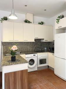 una cucina con armadi bianchi e una lavatrice/asciugatrice di SC Apartamento céntrico con balcón a Terrassa
