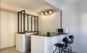een keuken met zwarte stoelen en een aanrecht met een magnetron bij Studio Carignan in Bandol