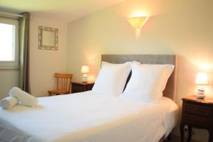 a bedroom with a large white bed with two lamps at Source de la Vallée in Sadroc