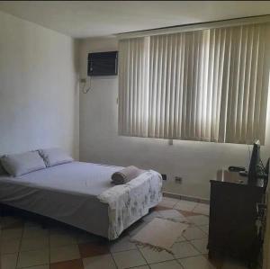 um quarto com uma cama, uma televisão e uma janela em Quattrô suítes Santos em Santos