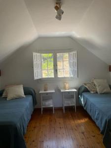 um quarto com duas camas e uma mesa e duas janelas em Casa rural La Frambuesa em Galaroza