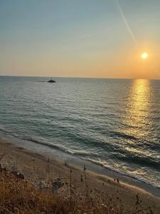 a beach with the sun setting over the ocean at Dionisos Hotel in Mitikas