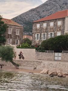 a man riding a motorcycle on a wall next to a building at Studio Apartman Ivanka in Orebić