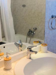 ein Waschbecken mit einem Spiegel und einer Badewanne in der Unterkunft Lydia House in Korinthos