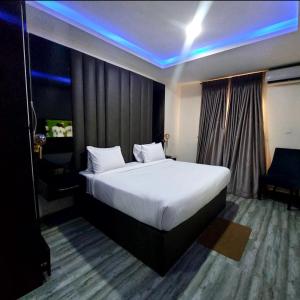 - une chambre avec un grand lit blanc et une lumière bleue dans l'établissement Ziroc Apartments Lekki Phase 1, à Lagos