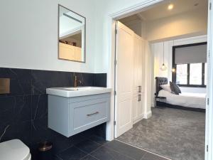 een badkamer met een wastafel, een spiegel en een bed bij Black Horse Apartments in Knaresborough