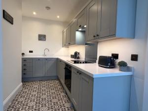 una cocina con armarios grises y encimeras blancas en Black Horse Apartments, en Knaresborough