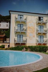 una mujer tendida en una piscina frente a un edificio en Stella D'Oro - Hotel & Apartments, en Tremosine Sul Garda