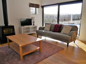 een woonkamer met een bank en een tafel bij Laundry Cottage in Aberlour
