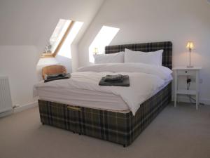 a bedroom with a large bed with a plaid blanket at Laundry Cottage in Aberlour