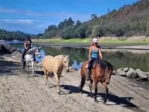 dos personas montando caballos en una playa cerca de un río en Encontro no Rio, en Póvoa de Midões