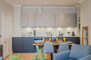 a kitchen with a table with chairs and blue cabinets at Dragon Suites Luxury Serviced Apartments at Walker Street in Edinburgh