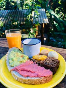 un plato amarillo con un sándwich y un vaso de zumo de naranja en Sitio Simple Life en Ubatuba