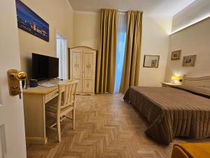 Una habitación de hotel con una cama, un escritorio y un televisor. en Resort del Roster, en Florencia