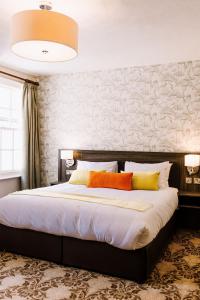 a bedroom with a large bed with orange and yellow pillows at The Bull Hotel in Stony Stratford