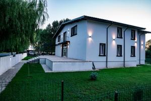 a large white house with a grassy yard at Pensiunea 77 