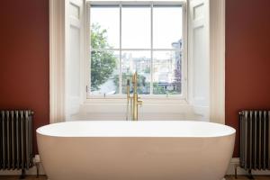 a white bath tub in front of a window at Dragon Suites Luxury Serviced Apartments at Walker Street in Edinburgh