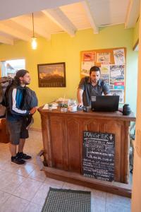 dos hombres parados en una caja registradora en un restaurante en Hostel Wenuy- en El Chaltén