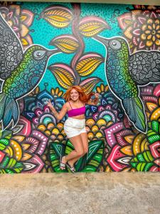 LS Villas Hotel & Spa في أغواز دي ساو بيدرو: امرأة تقف أمام لوحة جدارية