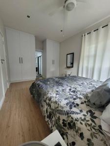 a bedroom with a large bed with a flowered blanket at Downstairs @38 in Port Elizabeth