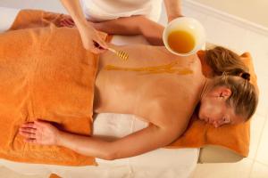 a woman laying on a towel with a cup of orange juice at Hotel Adria in Merano