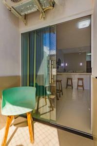 a green chair in a room with a kitchen at Apartamento Incrível in Salvador