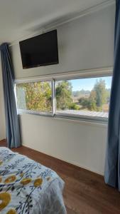 1 dormitorio con ventana grande y TV de pantalla plana en Cabaña con fogon y tinaja en plena naturaleza!, en Algarrobo