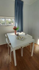 una mesa y sillas blancas en una habitación con ventana en Cabaña con fogon y tinaja en plena naturaleza! en Algarrobo