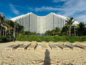 a group of chairs on the beach in front of a hotel at The Cam Ranh Resort all Luxury Service in Miếu Ông