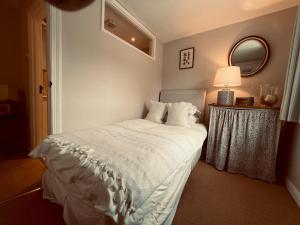 - une chambre avec un lit blanc et un miroir dans l'établissement Pass the Keys Scallop Cottage Oasis of Calm, à Rye