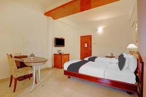 a bedroom with a bed and a table and a desk at Hotel Indraprastha in Trivandrum