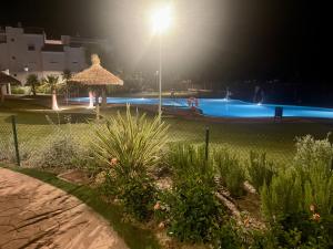 una piscina por la noche con luz en Anpartamento con Encanto Costa Ballena, en Costa Ballena