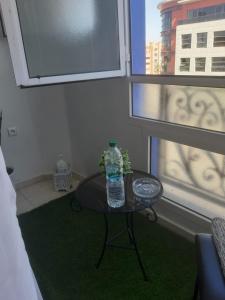 a bottle of water sitting on a table in front of a window at APPARTEMENT Hana Majorelle in Marrakesh