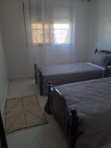 2 camas num quarto com uma janela e 2 tapetes em APPARTEMENT Hana Majorelle em Marrakech