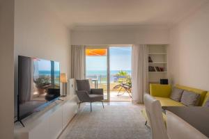 een woonkamer met een televisie en uitzicht op de oceaan bij Luxury flat on the Cote d'Azur in Villeneuve-Loubet
