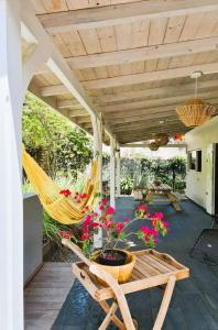 a porch with a hammock and a table and flowers at MADRAS LODGE in Le Diamant