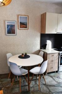 uma cozinha com uma mesa branca e cadeiras brancas em Evan's Suite em Glífa