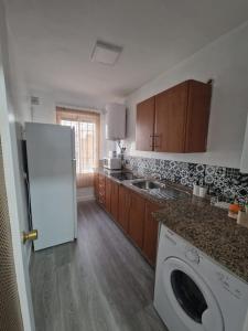 a kitchen with a white refrigerator and wooden cabinets at Apartamento Acogedor en Los Patios De San Basilio in Córdoba