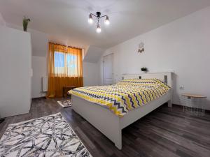 - une chambre avec un lit et une couette jaune et blanche dans l'établissement Casa Maria Sarata Monteoru, à Sărata-Monteoru