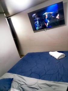 Hospedaje 51b في بوغوتا: غرفة نوم مع سرير وتلفزيون على الحائط