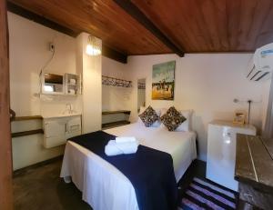 um quarto com uma cama branca e um lavatório em Pousada Raiz Forte em Caraíva