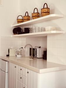 una cocina con fregadero y cestas en las estanterías en Casa Di Manto Traditional Apartment, en Mykonos ciudad