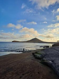 una persona caminando en una playa cerca del agua en Apartamento Victor Arico, en El Médano
