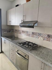 a kitchen with white cabinets and a stove top oven at Appartement de charme in Kenitra