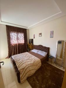 a bedroom with a bed and a large window at Appartement de charme in Kenitra