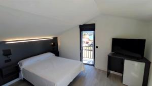 a bedroom with a bed and a flat screen tv at Apartamentos Dabarca Combarro in Combarro