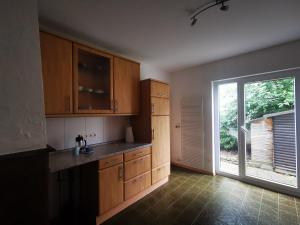 a kitchen with wooden cabinets and a large window at Charmantes Ferienhaus Casa Ella mit Balkon Nähe Kinderklinik in Siegen