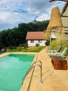a swimming pool with chairs and a house at Casa rural La Frambuesa in Galaroza