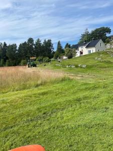 a field of green grass with a house and a tractor at Sjarmerende gårdsbruk omgitt av vakker natur in Molde